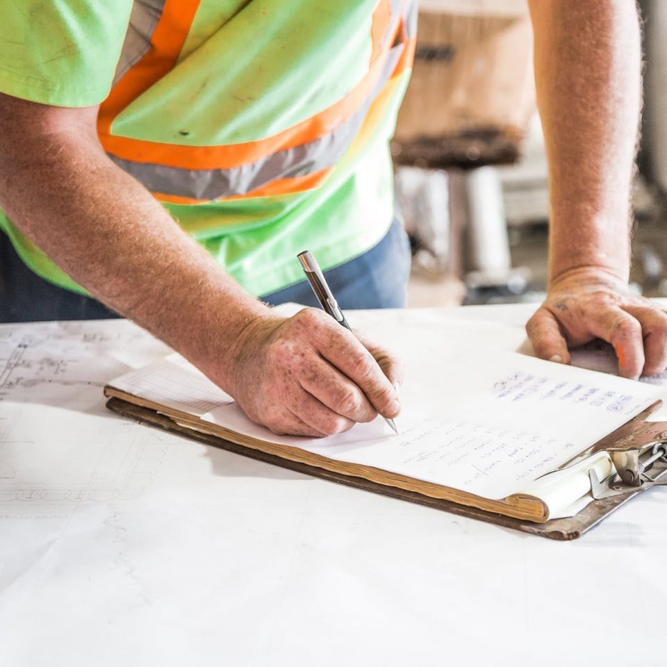 person writing on paper on top of table